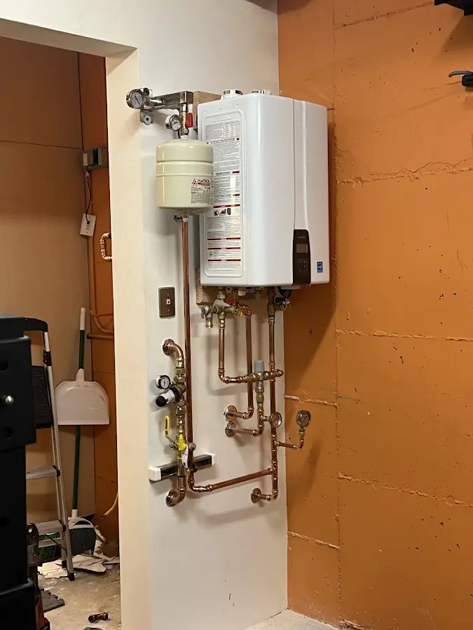 Plumbing technician inspecting water heater connections in Watauga